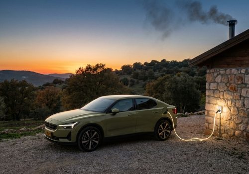 רכב חשמלי נטען באמצעות מטען נייד (כבל סבתא) ליד צימר בצפון, המדגים את החופש והגמישות בטעינה.